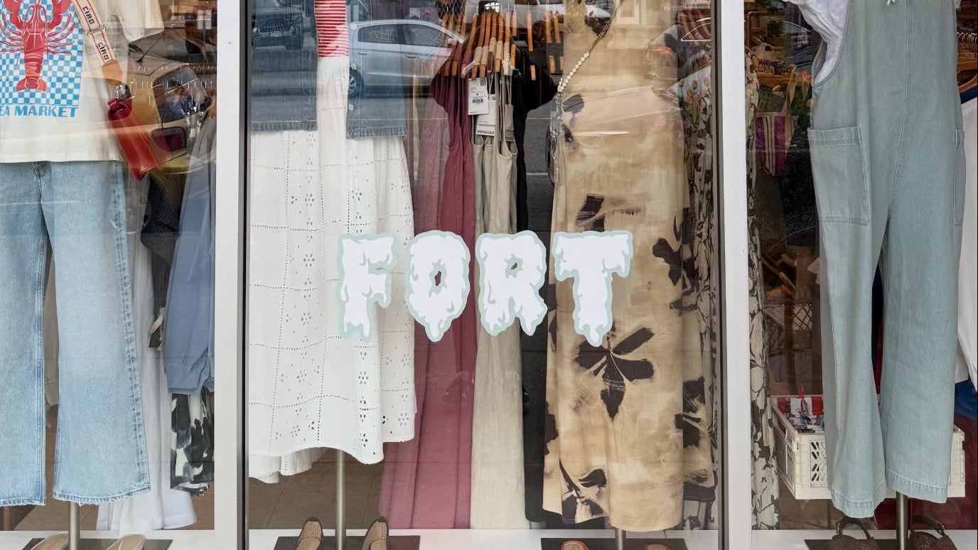 Storefront display with mannequins wearing clothing and 'For Sale' signs.